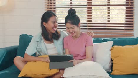 Young-Lesbian-lgbtq-Asian-women-couple-using-tablet--watching-movie-on-internet-together-while-lying-sofa-in-living-room.