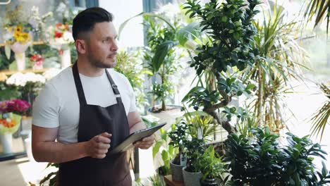 Slow-motion-of-man-flower-store-owner-using-tablet-at-work-touching-screen