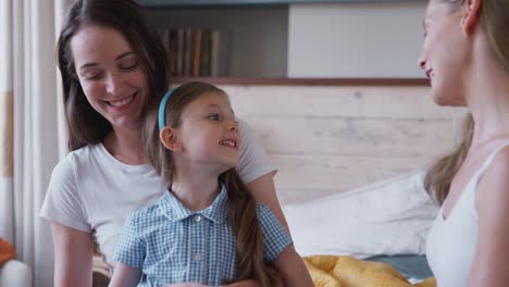 Pareja-femenina-del-mismo-sexo-en-casa-en-el-dormitorio-preparando-a-su-hija-para-la-escuela