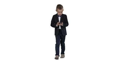 Niño-pequeño-en-traje-caminando-y-usando-el-teléfono-inteligente-sobre-fondo-blanco