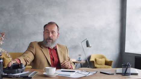 Stylish-Aged-Man-Using-Gadgets-at-Workplace