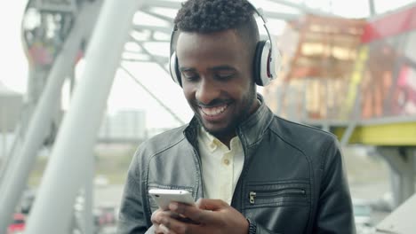 Slow-motion-of-African-American-man-using-smartphone-laughing-outdoors