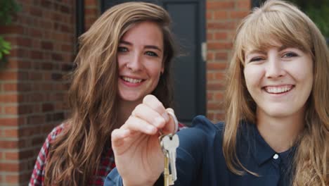 Porträt-von-aufgeregten-schwulen-weiblichen-Paar-stehen-vor-new-Home-Holding-Keys-zusammen