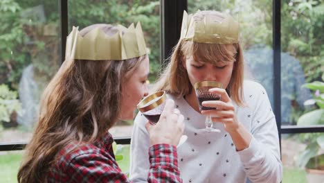 Pareja-gay-mujer-sentada-alrededor-de-la-mesa-para-la-cena-de-Navidad-susurrando-y-haciendo-tostadas