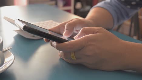 Frau-mit-Smartphone-auf-dem-Schreibtisch-zu-Hause.