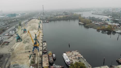 Industrial-part-of-city-with-port-cranes-and-barge-transporting-river-sand.-Industrial-concept