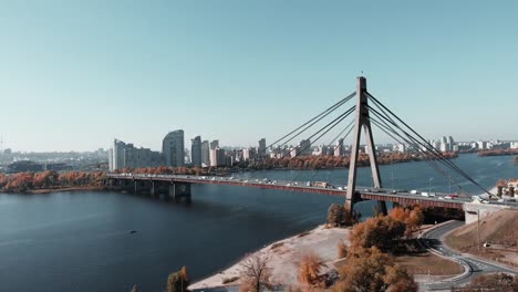 Große-Betonbrücke-mit-Stahlseilschleppnetzen,-die-zwei-Ufer-der-Großmetropole-verbinden.-Luft-Drohnenansicht-der-Brücke-mit-viel-Befahrenem-Autoverkehr,-Kiew,-Ukraine