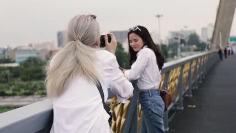 Asian-lesbian-couples-enjoying-traveling-using-film-camera-taking-a-photo.-Two-beautiful-young-women-having-fun-in-vacation-time.