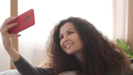 Frau-macht-Selfie-liegend-im-Bett-zu-Hause