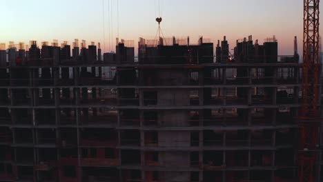 Aerial-Shot-of-the-Building-in-the-Process-of-Construction.-Labor-working-in-big-construction-site.-In-the-Background-Working-Crane-and-city