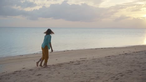 Zwei-junge-glückliche-Frauen-tanzen-und-spaßigen-sich-am-Strand-bei-Sonnenuntergang.