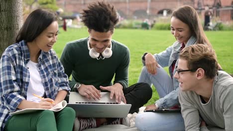 Portrait-of-Multiethnic-group-of-excited-adult-and-happy-american-friends-hanging-out-on-university-space-colloborating-using-laptop