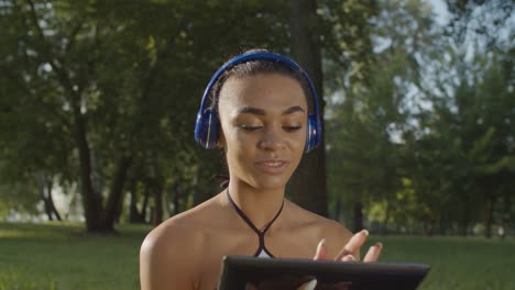 Hübsche-Frau-in-Kopfhörern-genießen-Musik-im-Park