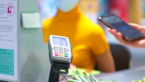 Close-up,-paying-for-purchases-using-a-smartphone,-nfc.-Phone-is-brought-to-the-payment-terminal,-contactless-payment-in-the-supermarket.-4k,-ProRes