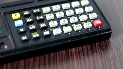 Hand-operates-old-retro-calculator-at-workstation