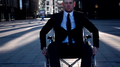 Disabled-businessman-move-in-wheelchair-on-camera-outdoor-near-business-centre