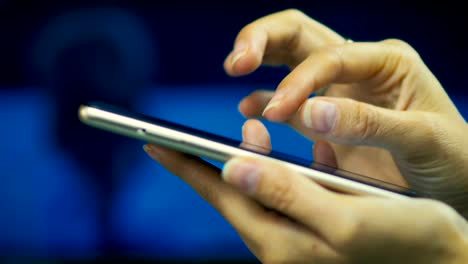 Close-up-of-a-young-girl-browses-pages-on-the-internet-on-smart-phone-on-a-laptop-screen-background.