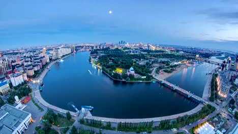 Aumento-de-vista-sobre-centro-de-la-ciudad-con-vista-al-río-y-Parque-y-el-distrito-de-negocio-día-a-la-noche-Lapso-de-tiempo,-Asia-Central,-Kazajstán,-astaná