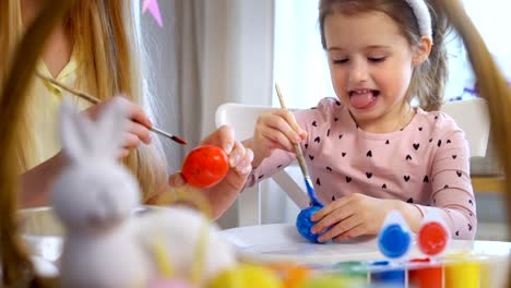 Frohe-Ostern!-Mutter-und-ihre-kleine-Tochter-tragen-lustige-Hasenohren-Ostereier-färben