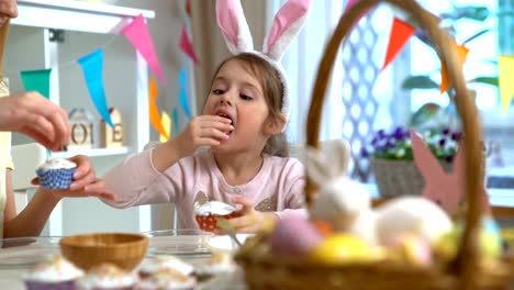 Joven-madre-y-su-pequeña-hija-con-orejas-de-conejo-divertidos-cocinar-cupcakes-de-Pascua