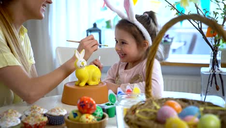 Frohe-Ostern!-Mutter-und-ihre-kleine-Tochter-mit-Hasenohren-malen-Osterhase