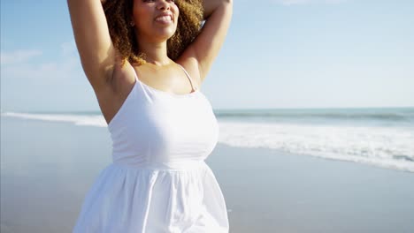 Ethnic-female-walking-barefoot-and-paddling-in-ocean