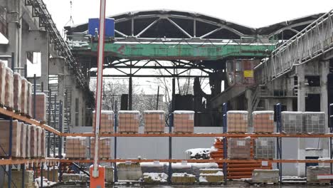 Building-and-construction-materials-for-sale-stored-on-metal-shelves-outdoors-in-a-warehouse-yard-together-with-wooden-pallets-for-loading,-distribution-and-storage