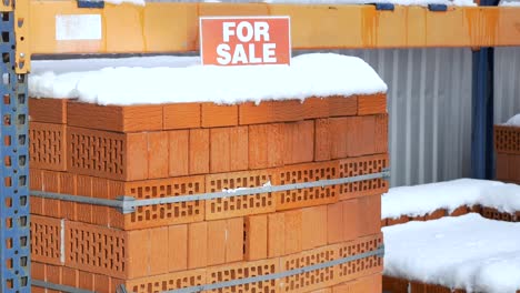 Pila-de-ladrillos-de-arcilla-naranja-con-nieve-"en-venta"-palabras