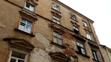 Aged-building-facade-with-broken-windows-in-old-historical-town,-loneliness