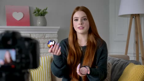 Young-red-haired-girl-blogger,-smiling,-talking-at-the-camera,-showing-a-new-purchase,-cosmetics,-Eyeshadow-Pallet,-home-comfort-in-the-background.-60-fps