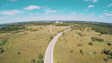 Aerial-view-of-old-style-white-car-riding-on-road-trough-nature