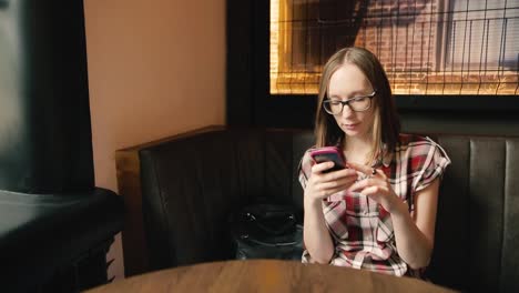 Trendy-smiling-girl-in-glasses-chatting-in-social-networks-or-reading-something