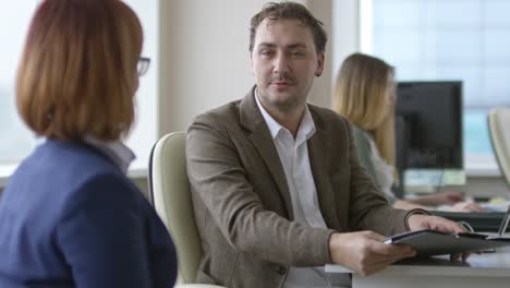 Behinderte-Frau-mit-Kollegen-sprechen-und-arbeiten-am-Schreibtisch