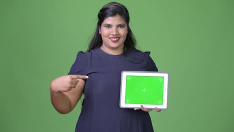 Young-overweight-beautiful-Indian-businesswoman-against-green-background