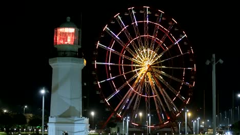 Illuminated-ferris-wheel-and-lighthouse,-Batumi-landmark-architecture,-tourism