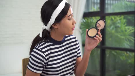 Blogger-de-belleza-actualmente-cosméticos-de-belleza-sentada-en-frente-la-cámara-para-la-grabación-de-vídeo.-Hermosa-mujer-use-cepillo-mientras-revisión-maquillaje-tutorial-transmiten-video-en-vivo-en-red-social-por-internet.