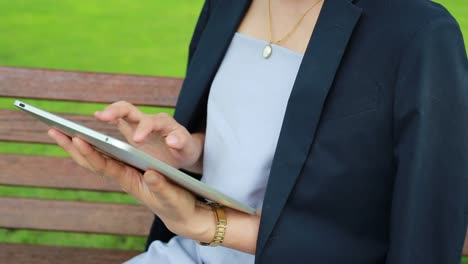 Junge-attraktive-Frau-mit-Tablet-PC-sitzen-im-Garten