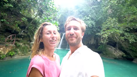 Young-couple-taking-selfie-portrait-with-a-beautiful-waterfall