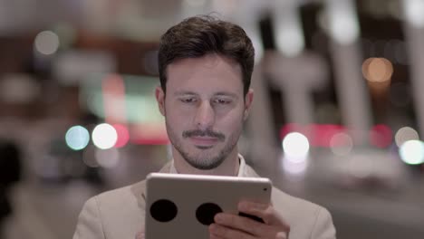 Handsome-young-businessman-writing-texts-on-digital-tablet-in-public-space