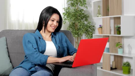 Mujer-feliz-escribiendo-en-la-computadora-portátil-en-casa