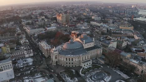 Vista-aérea-en-el-teatro-de-ópera-y-ballet-de-Odessa-durante-el-invierno-en-puesta-de-sol,-tiro-de-seguimiento