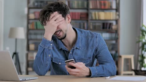 Man-Upset-for-Loss-while-Using-Smartphone