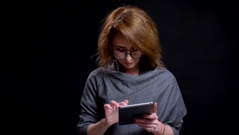 Retrato-de-acercamiento-de-la-mujer-adulta-atractiva-que-navega-Internet-en-la-tableta-casualmente-entonces-mirando-al-camarógrafo-y-sonriendo