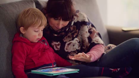 Mutter-mit-ihrem-Sohn-mit-Tablet-auf-Sofa-zu-Hause