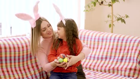 mother-looking-at-daughter-holding-her-hands-which-are-Easter-eggs.