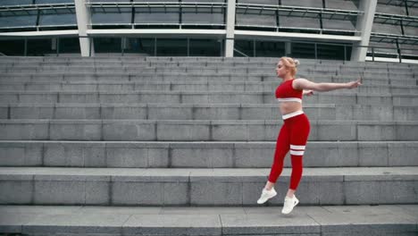 Gemischte-Rasse-blond-lächelnde-Frau-mit-roter-Sportbekleidung-macht-Gymnastik