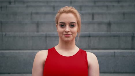 Portrait-of-plus-size-mixed-race-blond-smiling-woman-wearing-red-sportswear-looking-at-camera