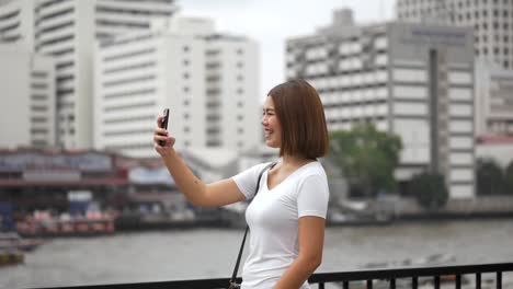 Touristische-junge-asiatische-Frau,-die-mit-dem-Smartphone,-das-sich-mit-Freunden-in-den-Sommerferien-in-den-sozialen-Medien-verbindet,-videochat-macht.