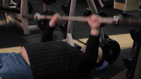 Cheerful-fat-man-performs-the-wrong-bench-press-in-the-gym