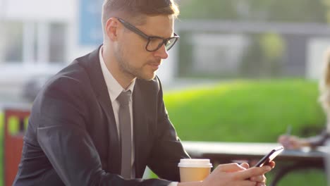 Businessman-in-Glasses-Using-Smartphone-Outdoors